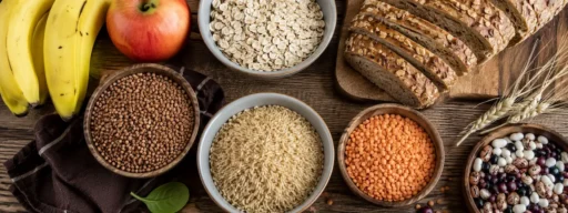 Продукты, богатые углеводами: крупы, цельнозерновой хлеб, бобовые и фрукты на столе